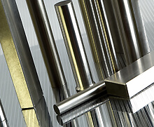 Various titanium rods and bars, including cylindrical and rectangular shapes, standing on a reflective surface.